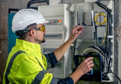 man-electrical-technician-working-switchboard-with-fuses-uses-tablet_11zon